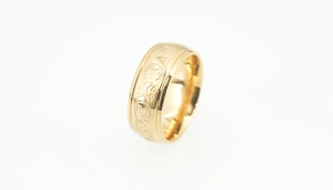 Detailed macro shot of a wide gold-plated steel ring with floral scroll engravings