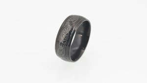 Macro shot of men's black titanium steel ring featuring detailed laser-engraved scroll patterns