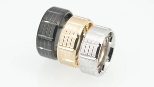 Detailed view of three stainless steel rings in black, gold, and silver with grid textures