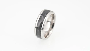 Détail d'une bague en acier titane argenté avec insert en fibre de carbone et bords polis