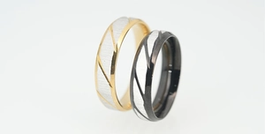 Detail showing gold and black titanium steel rings with brushed texture and diagonal grooves