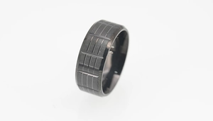 Detailed view of black titanium ring featuring vertical stripes and industrial mesh texture
