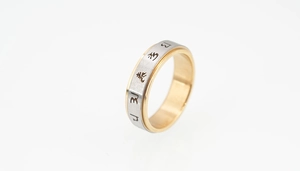 Détail d'une bague rotative bicolore avec symboles Mantra gravés et texture brossée