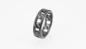 Macro detail of gunmetal black stainless steel ring featuring a cuban chain link design