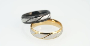 Detail of black and gold titanium steel rings with silver brushed finish and diagonal grooves