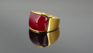 Makroaufnahme eines klobigen Goldrings mit einem großen roten Cabochon-Edelstein