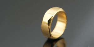 Macro shot of geometric faceted gold titanium ring on reflective dark surface