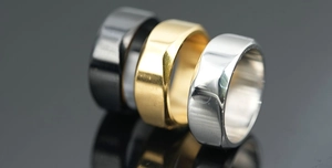 Macro shot of geometric faceted titanium steel rings in black, gold, and silver finishes