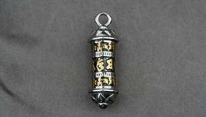 Close-up of titanium steel cylinder pendant featuring gold mantra text and lotus patterns