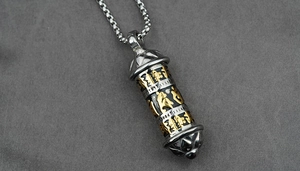 Macro shot of bicolour cylindrical pendant with engraved Buddhist mantras and steel chain