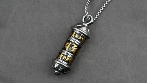 Macro detail of cylinder pendant with golden Sanskrit engraving and lotus motif
