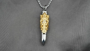 Macro detail of bullet pendant with gold hollow carving and clear crystal on silver chain