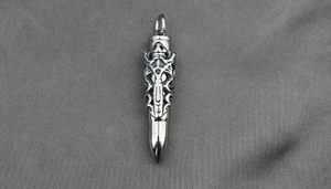 Detail of silver titanium steel bullet pendant with intricate gothic dragon carvings