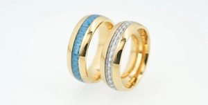 Detail of gold titanium rings with blue and silver carbon fiber inlay for couples