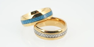 Detail of titanium steel rings featuring blue and silver carbon fiber inlay and gold finish