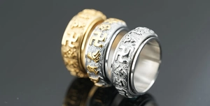 Macro detail of spinning titanium steel rings with Buddhist mantra and gold relief finish