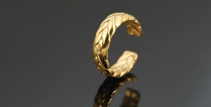 Macro shot of gold wheat ear pattern ring with adjustable open band and polished texture