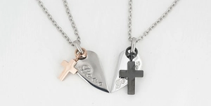 Detail of coupled heart necklaces with cross pendants and engraved Love Forever text