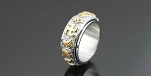 Macro detail of rotating stainless steel ring featuring golden religious symbols