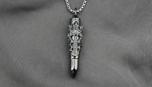 Detail shot of vintage silver bullet pendant with gothic sword engraving on a box chain