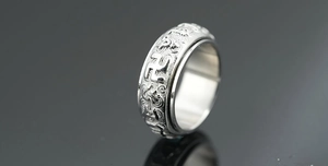 Macro detail of rotating silver titanium steel ring with engraved Buddhist symbols
