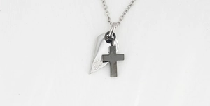 Macro detail of couple's pendant featuring silver heart wing and black cross charms