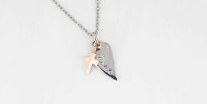 Detail view of double pendant necklace with silver heart Peace engraving and rose gold cross