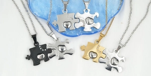 Dettaglio di collane a puzzle con cuore intrecciato in finiture argento, oro e nero