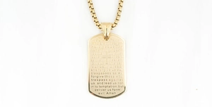 Close-up of gold military tag pendant with engraved cross and religious prayer text