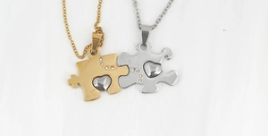 Dettaglio delle collane a cuore con pezzi di puzzle in oro e argento con intarsio di cristalli