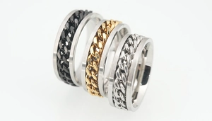 Detailed close-up of three rotating stainless steel chain rings in black, gold, and silver