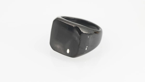 Vue macro d'une bague chevalière carrée noire polie montrant une finition brillante et épurée