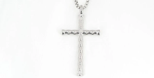 Gros plan du pendentif croix argenté avec texture géométrique et chaîne box
