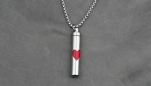 Macro shot of polished stainless steel cylinder pendant necklace with a red heart design