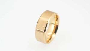 Close-up of golden wide titanium steel ring with brushed surface and mirror polished edges