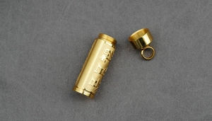 Detailed macro view of the gold cylindrical mantra pendant with embossed scriptures
