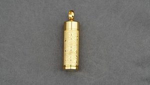 Detailed close-up of golden cylindrical pendant featuring engraved religious scriptures