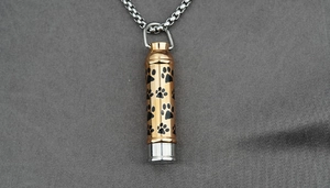 Vue macro d'un collier urne pour animaux or rose avec motifs de pattes noires gravés