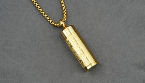 Macro view of golden cylinder pendant with deep engraved religious mantra scriptures