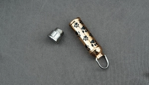 Vue macro du pendentif urne pour animaux en or rose avec empreintes noires et bouchon à vis