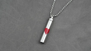 Macro detail of cylinder heart cremation necklace with red heart and box chain