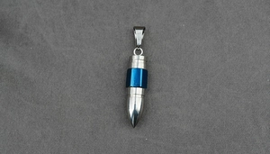 Detail of bullet-shaped stainless steel pendant with blue ring and brushed metal texture