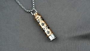Détail du pendentif urne bicolore avec motifs d'empreintes de pattes noires pour animaux