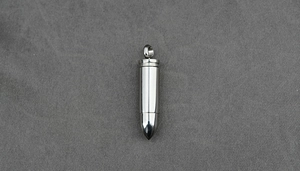 Close-up of a polished stainless steel bullet pendant with a mirror-like finish on fabric