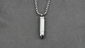Close-up of polished stainless steel bullet pendant on a robust box chain necklace