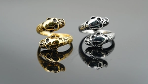 Macro shot of twin skull open rings with snake scale texture in gold and silver finish