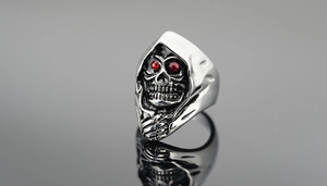 Detailed macro view of punk skull reaper ring featuring striking red gemstone eyes