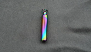 Macro detail of rainbow titanium steel perfume capsule pendant with hanging loop