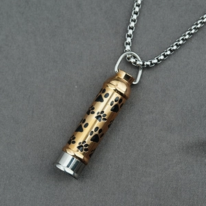 Collier urne en forme de balle en acier titane avec empreintes de pattes dorées