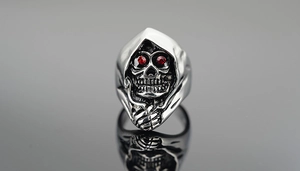 Close-up of gothic grim reaper skull ring with red gem eyes in polished stainless steel